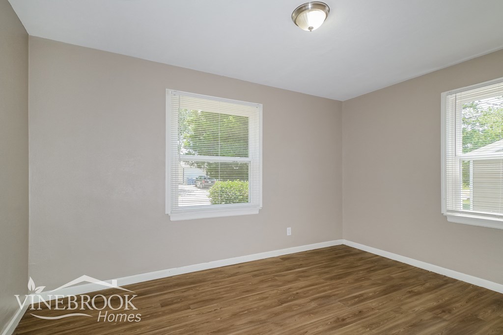 the living room of a home with wood flooring and two windows