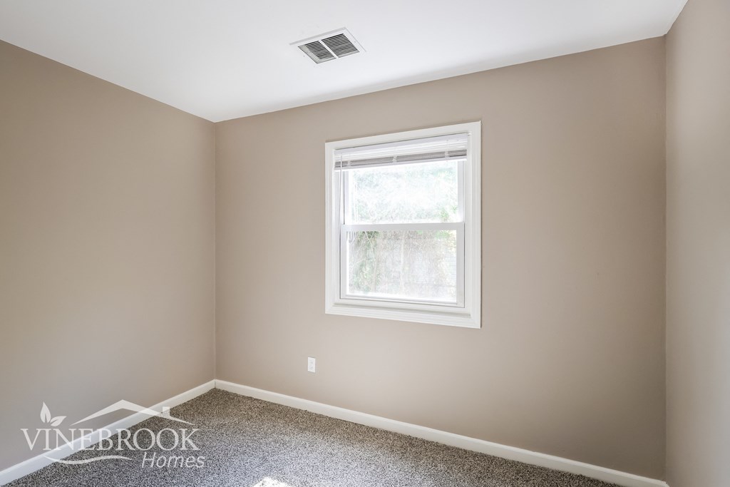 a bedroom with a window and a carpeted floor