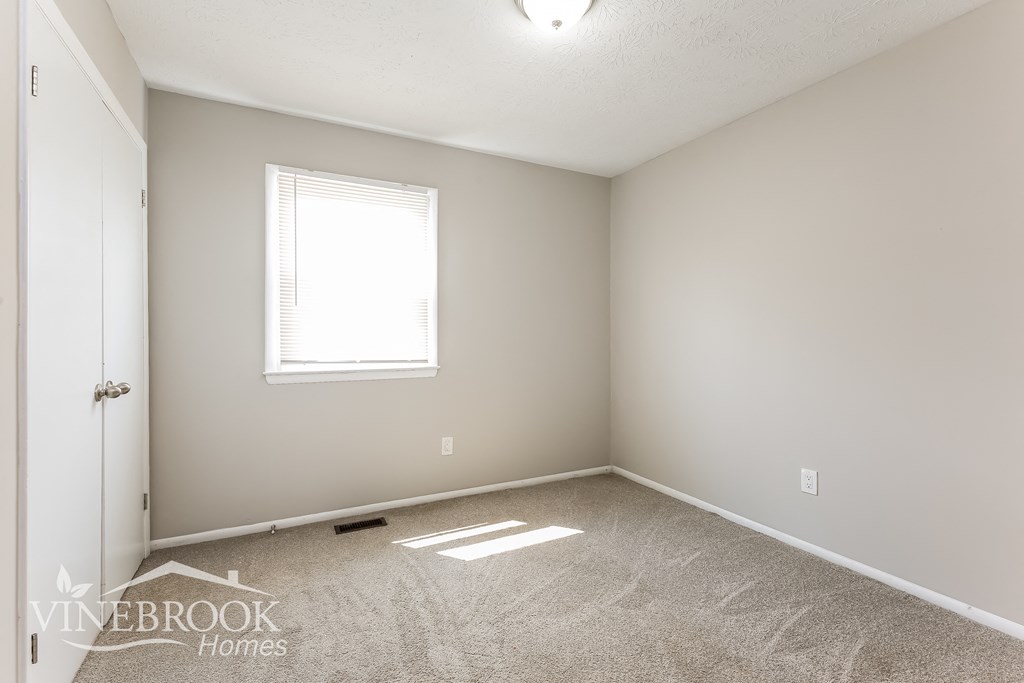 a bedroom with a carpeted floor and a window