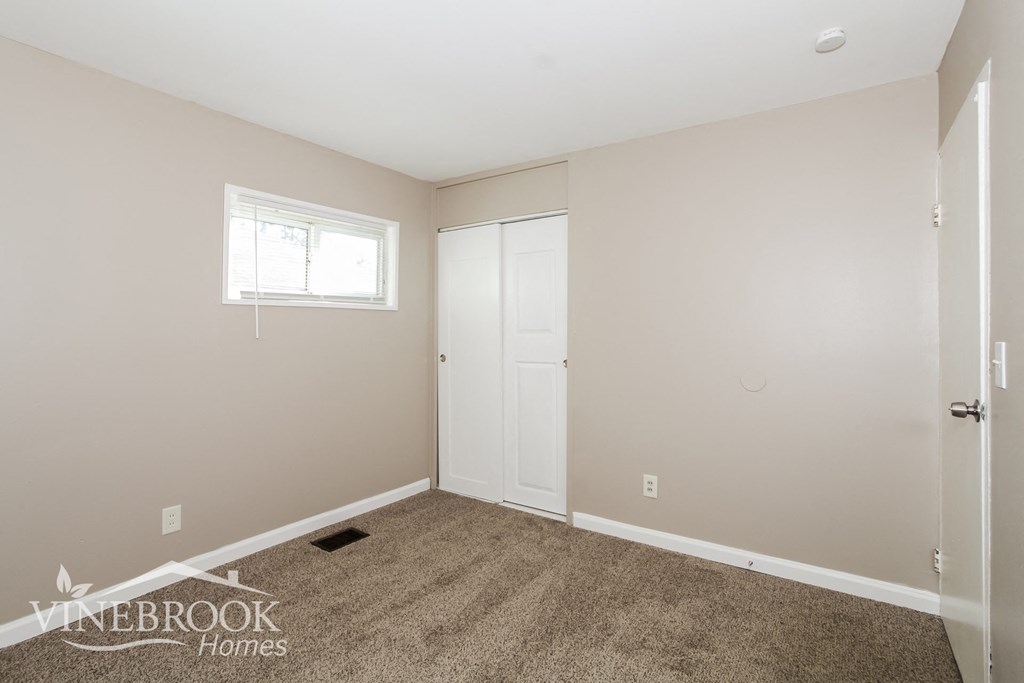 a bedroom with carpet and a door to a closet
