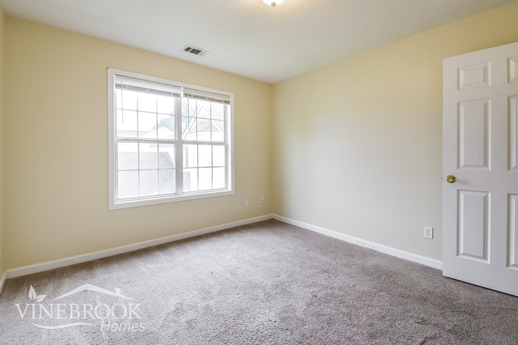 a bedroom with a carpeted floor and a window