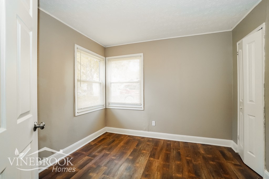 the living room of an empty house with wood floors and two windows