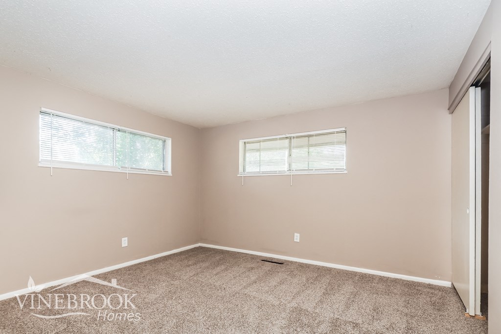 the upstairs bedroom has a carpeted floor and two windows