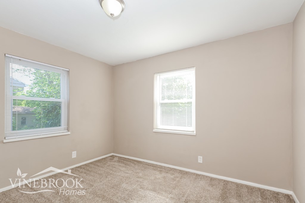 the second bedroom has a carpeted floor and two windows