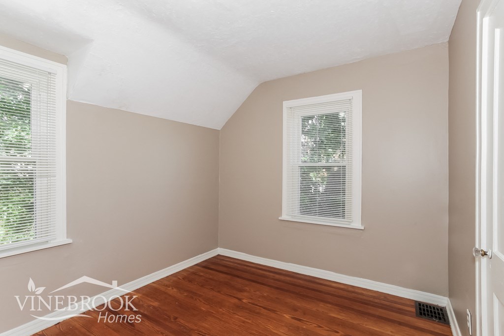 the second bedroom has a hardwood floor and a window