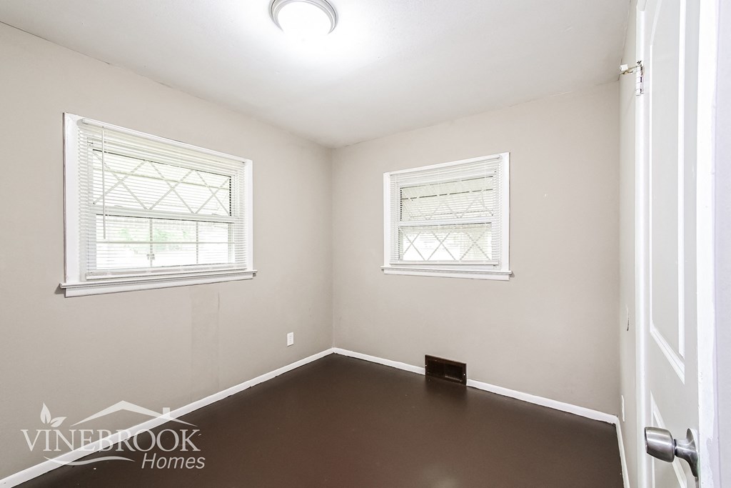 a empty room with a dark floor and two windows