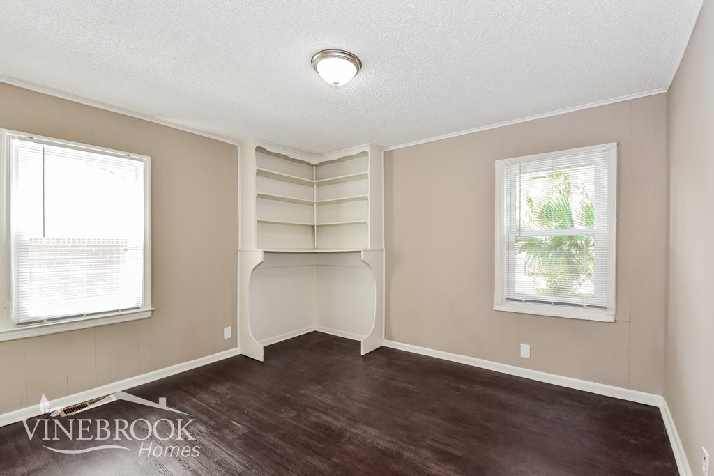 an empty room with a book shelf and a window