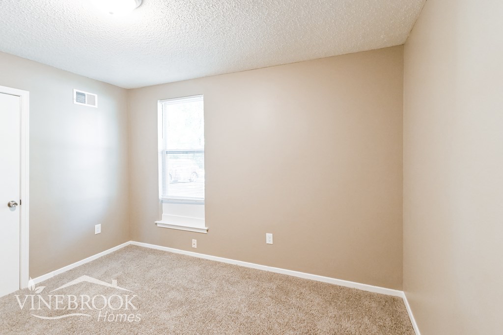 a bedroom with a carpeted floor and a window