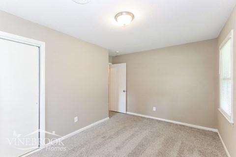 a spacious living room with carpet and a door to a closet