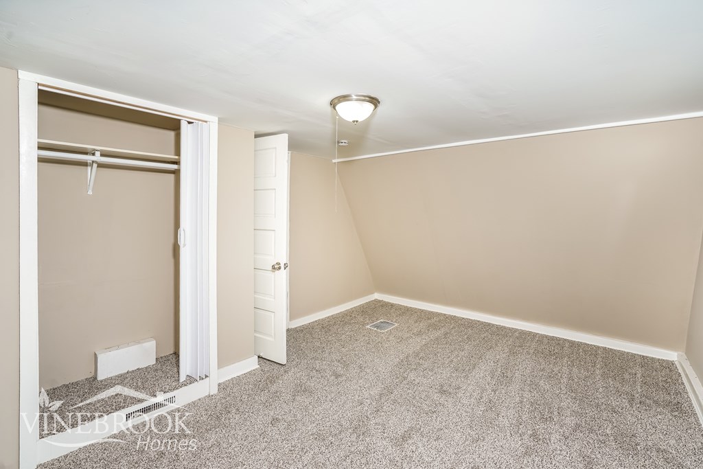 A bedroom with a carpeted floor and a white door.