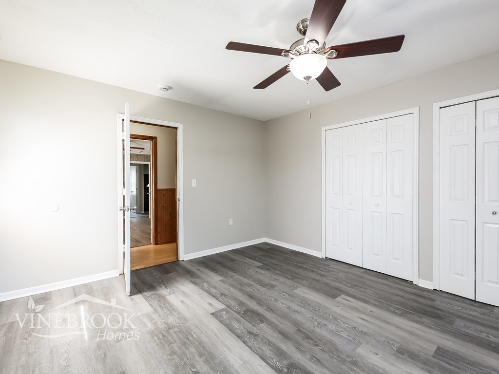 A room with a ceiling fan and wooden flooring.