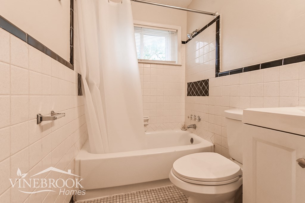 a white bathroom with a toilet and a tub and a sink