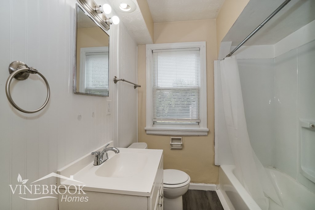 a white bathroom with a sink and a toilet and a shower