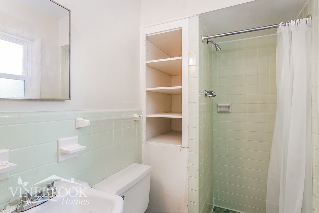 a bathroom with a shower and a sink and a toilet