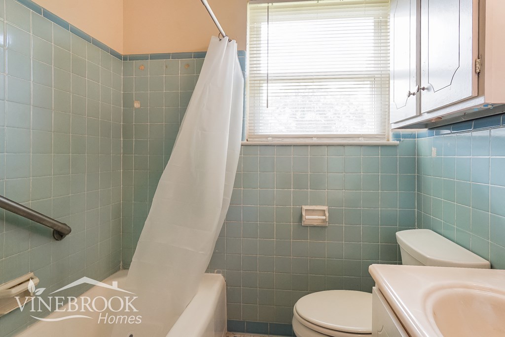 a bathroom with a toilet and a sink and a shower curtain