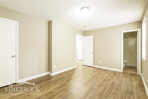 A spacious room with wooden flooring and white walls.