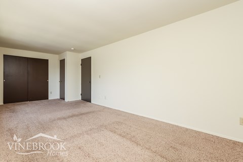 A room with a carpeted floor and two doors.