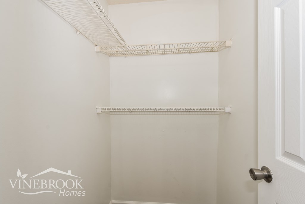 a walk in closet with white walls and a white door