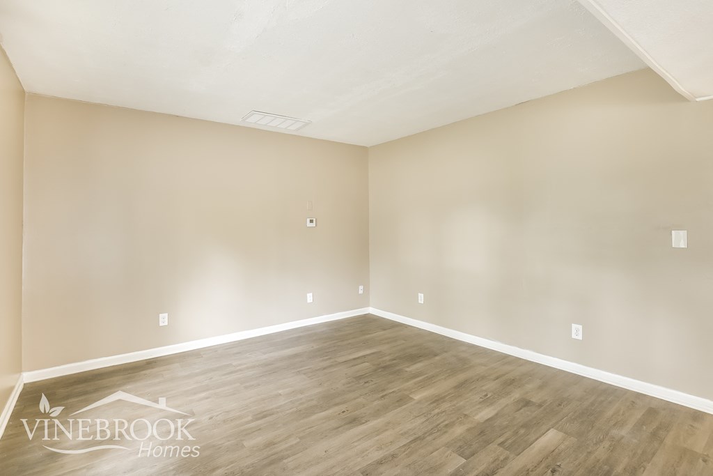the living room of an apartment with wood floors and white walls