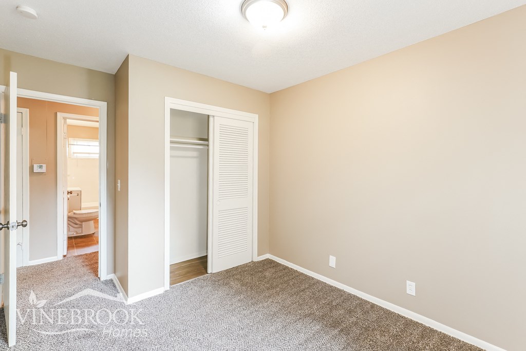 a bedroom with a closet and a door to the bathroom