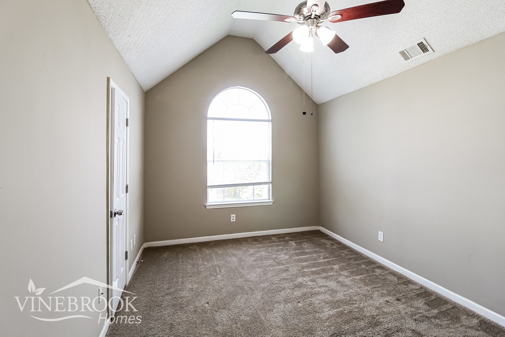 an empty bedroom with a ceiling fan and a window