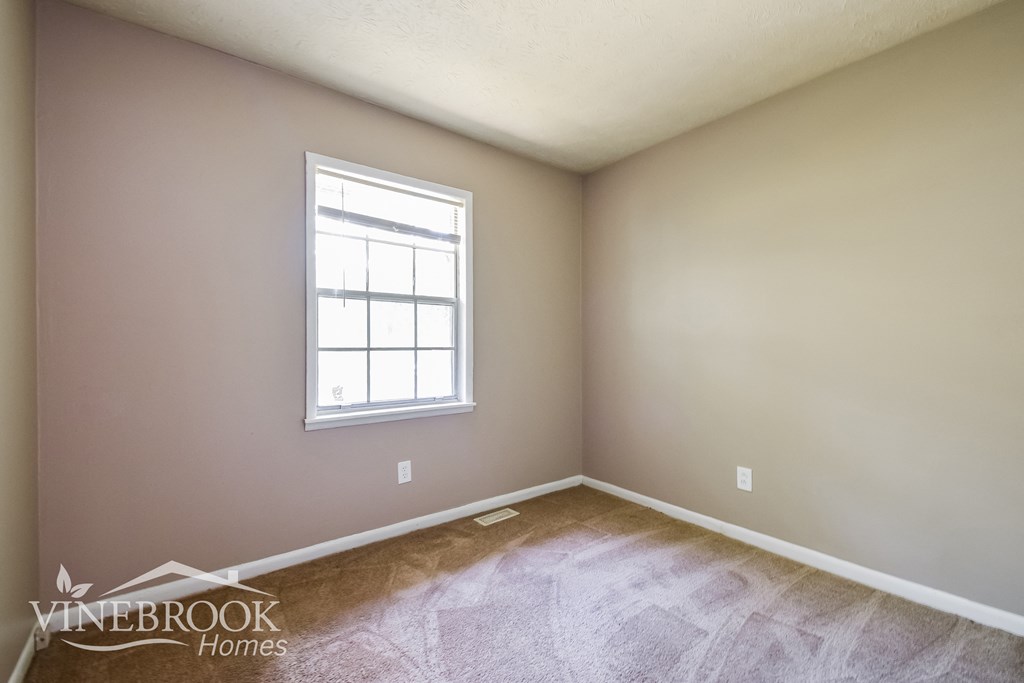 the living room of a home with a wooden floor and a window