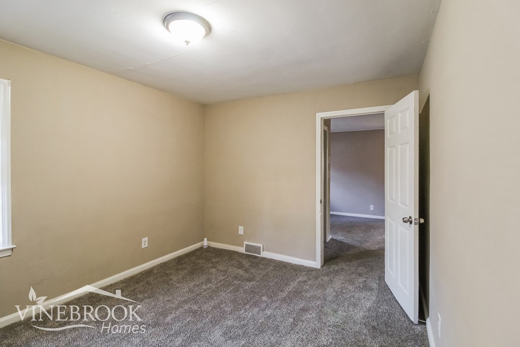 an empty room with carpet and a door to a closet