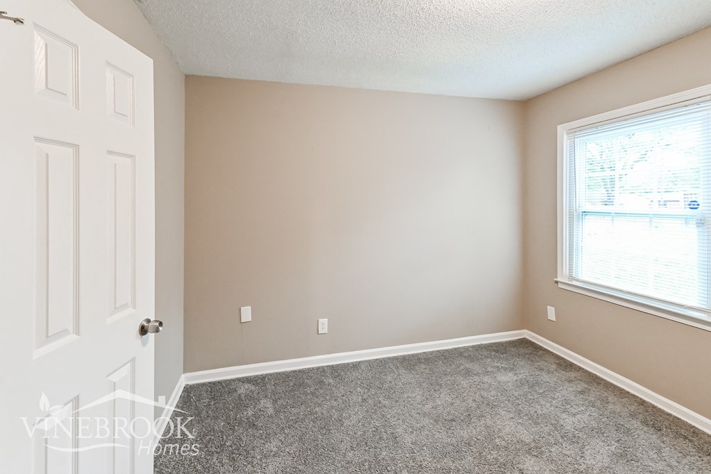 a bedroom with a carpeted floor and a window