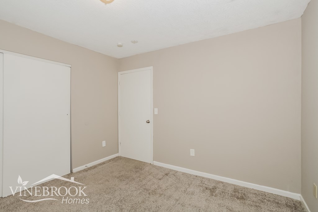 a bedroom with a carpeted floor and a door to a closet