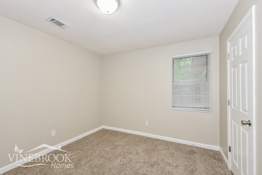 a bedroom with a carpeted floor and a window