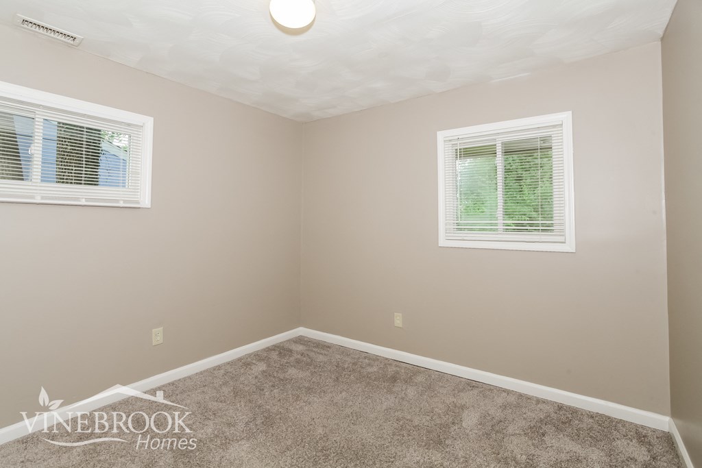 the upstairs bedroom has a carpeted floor and two windows