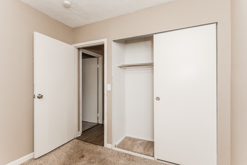an empty bedroom with white doors and a closet