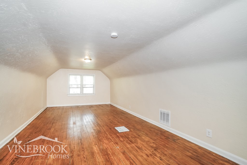 the living room with hardwood floors and white walls and a window