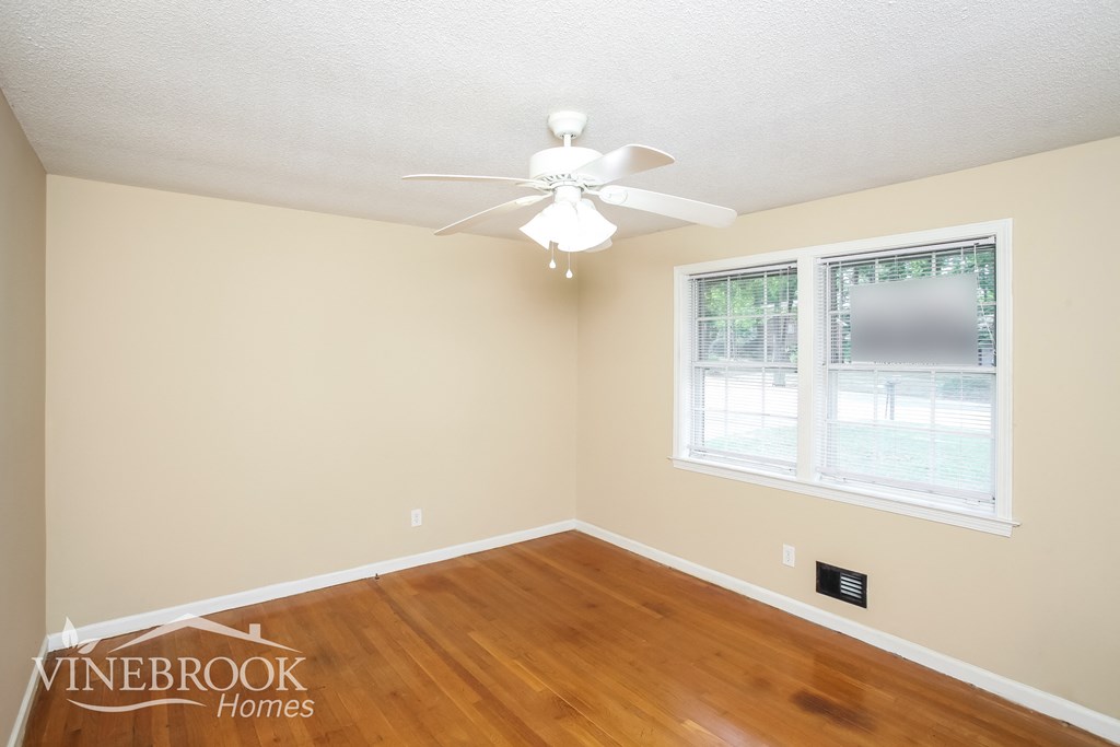 a bedroom with wood flooring and a ceiling fan