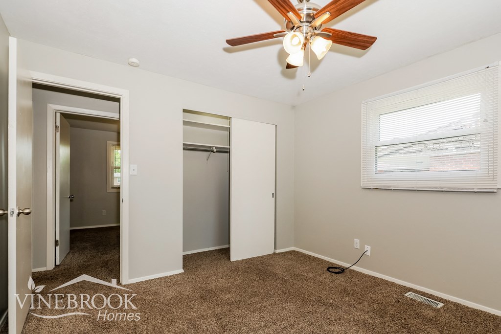 a bedroom with a ceiling fan and a closet