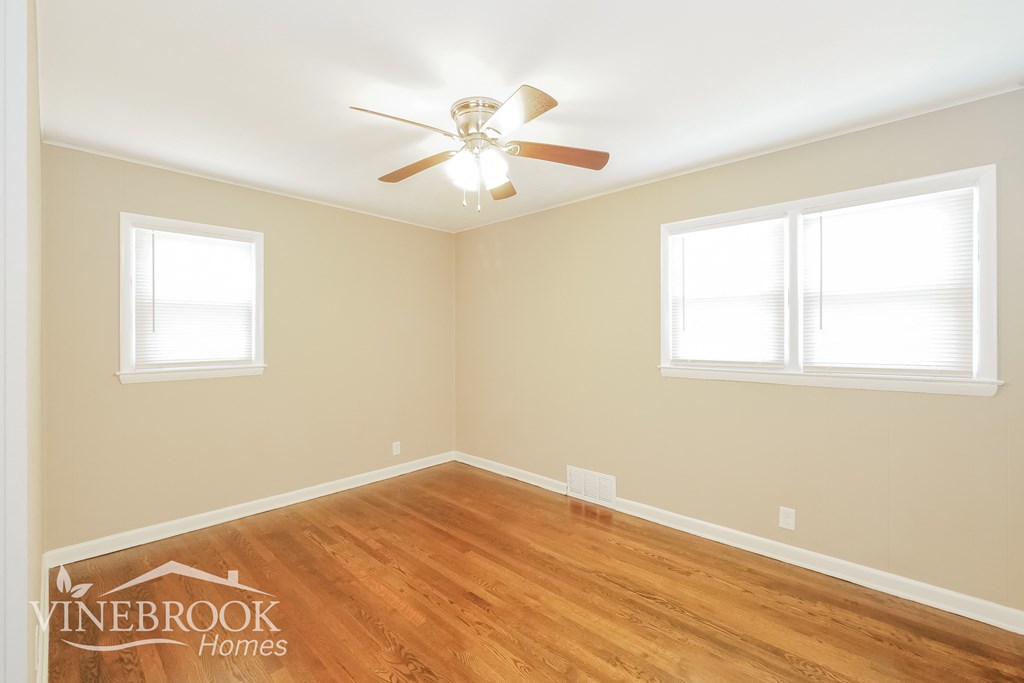 a bedroom with wood floors and a ceiling fan