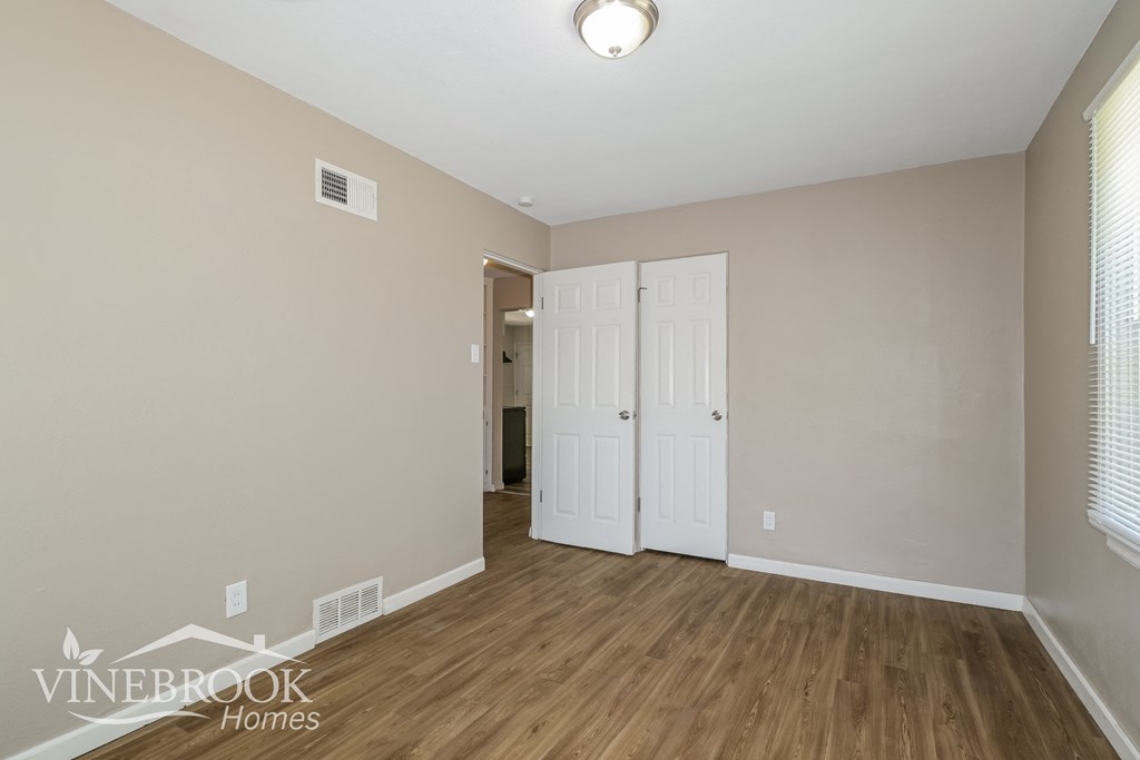 the living room of an apartment with wood flooring and white doors