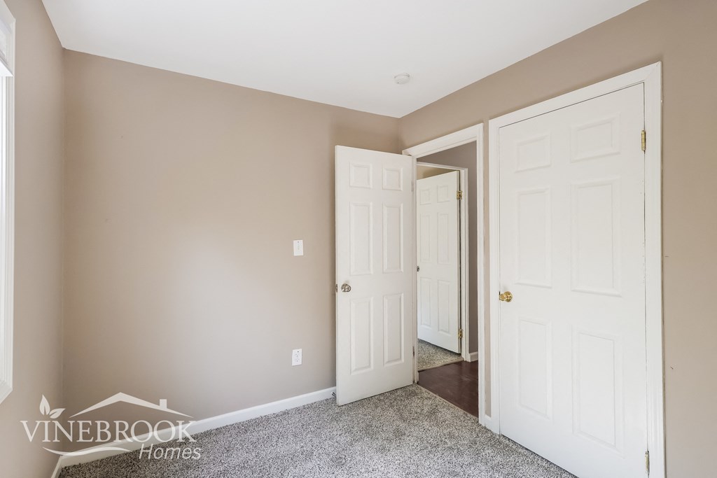a bedroom with two closets and two doors and a carpeted floor