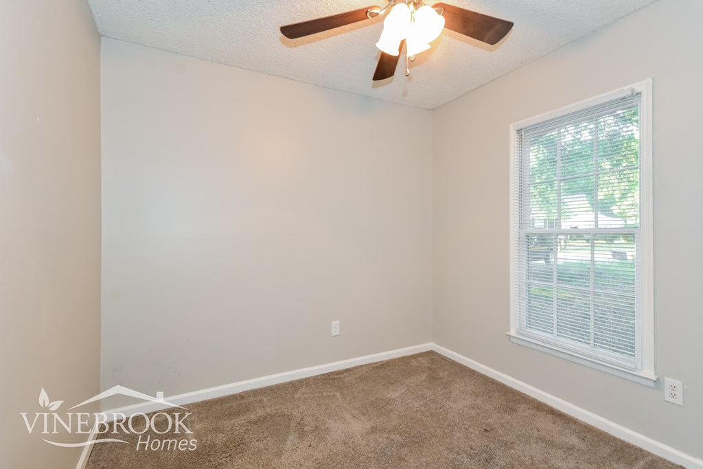 the living room of an empty home with a ceiling fan and a window