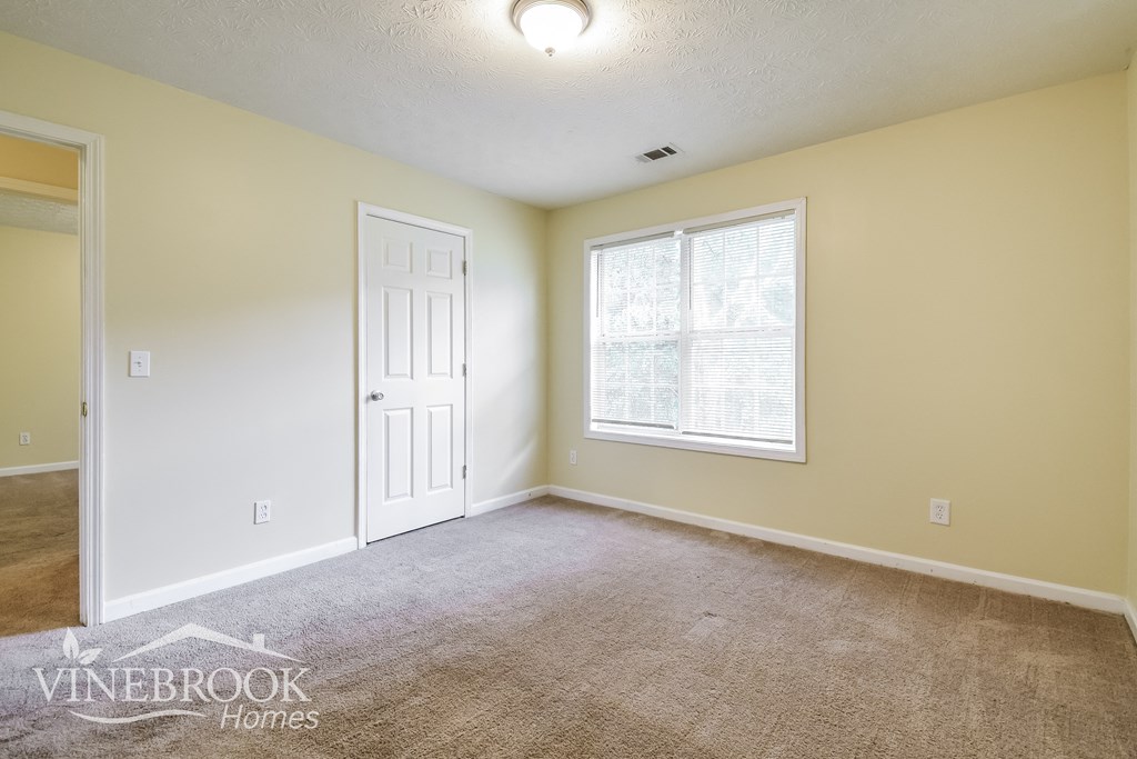 a empty living room with a white door and a window