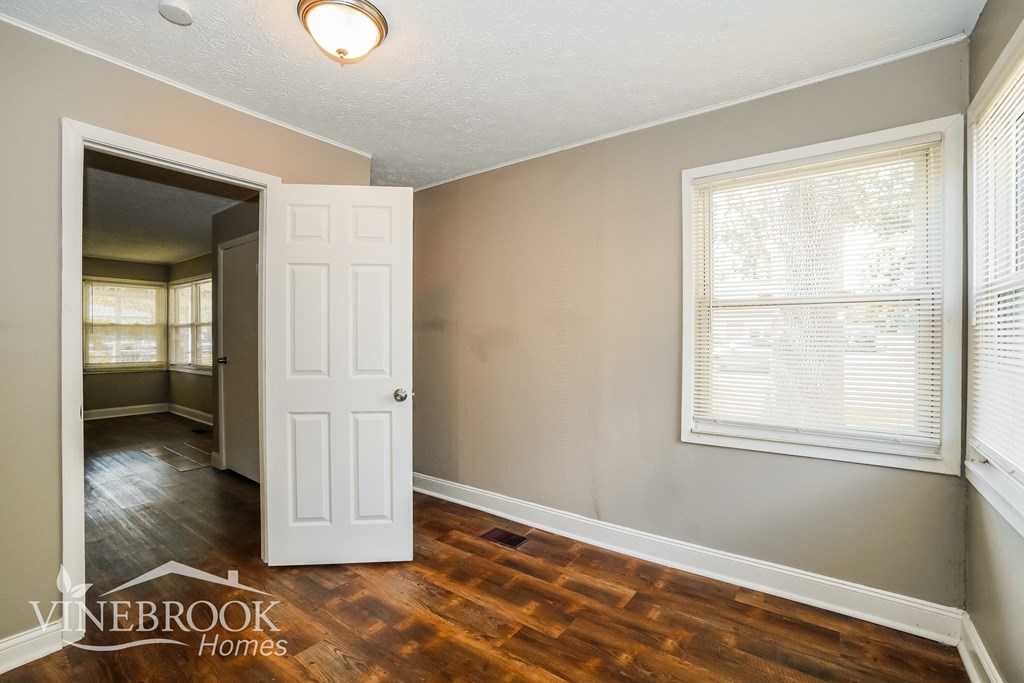 the living room and dining room of a house with wooden floors and a white door