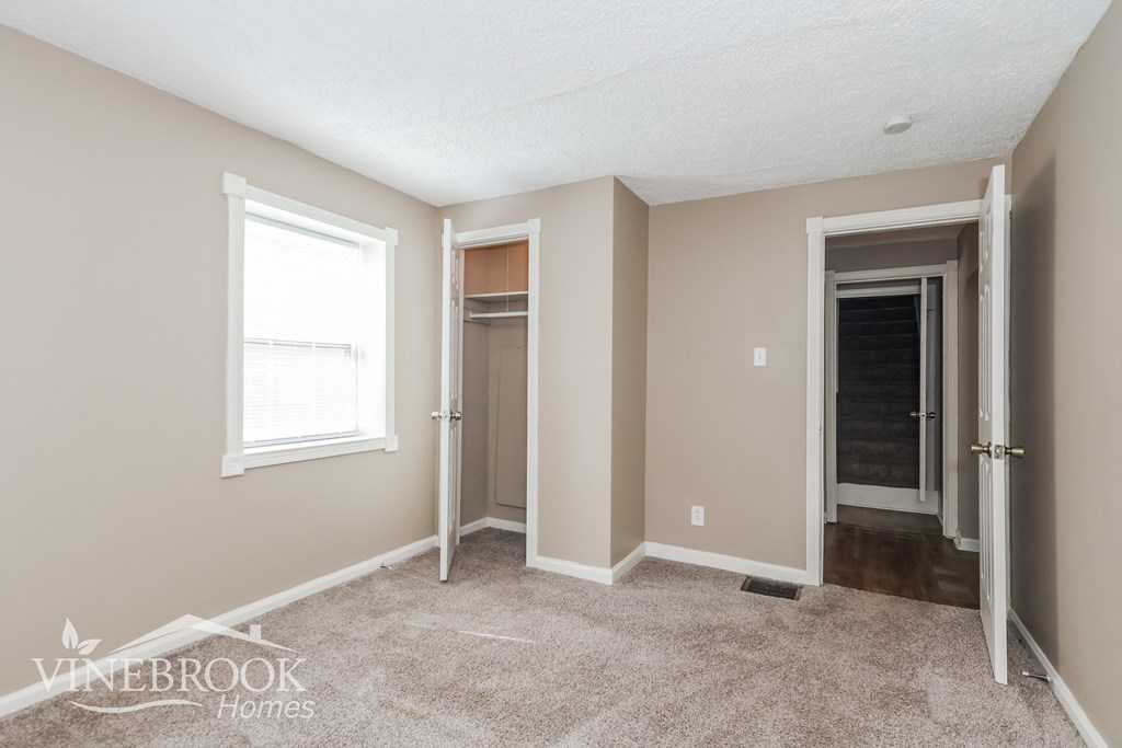 a bedroom with a carpeted floor and a closet and a window