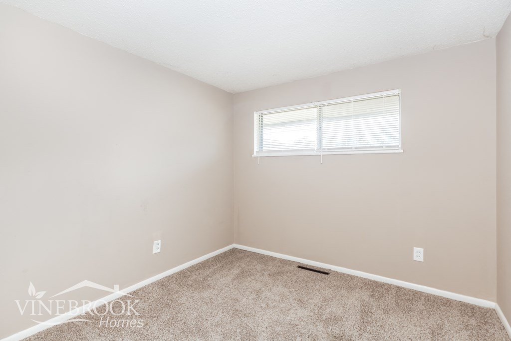 a bedroom with a carpeted floor and a window