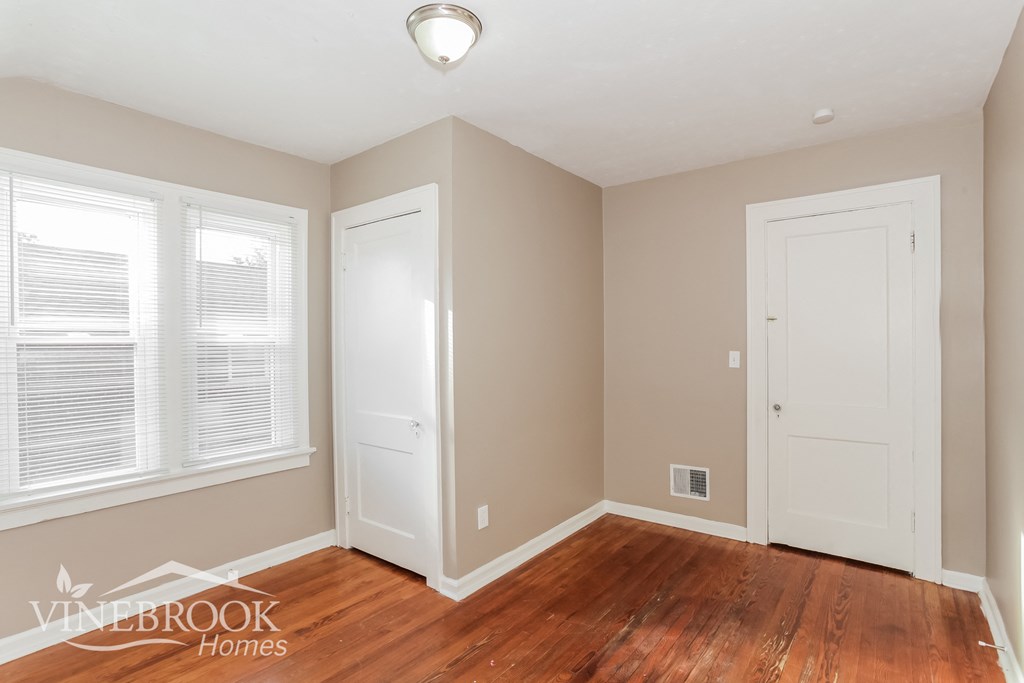 a bedroom with a hard wood floor and two white doors