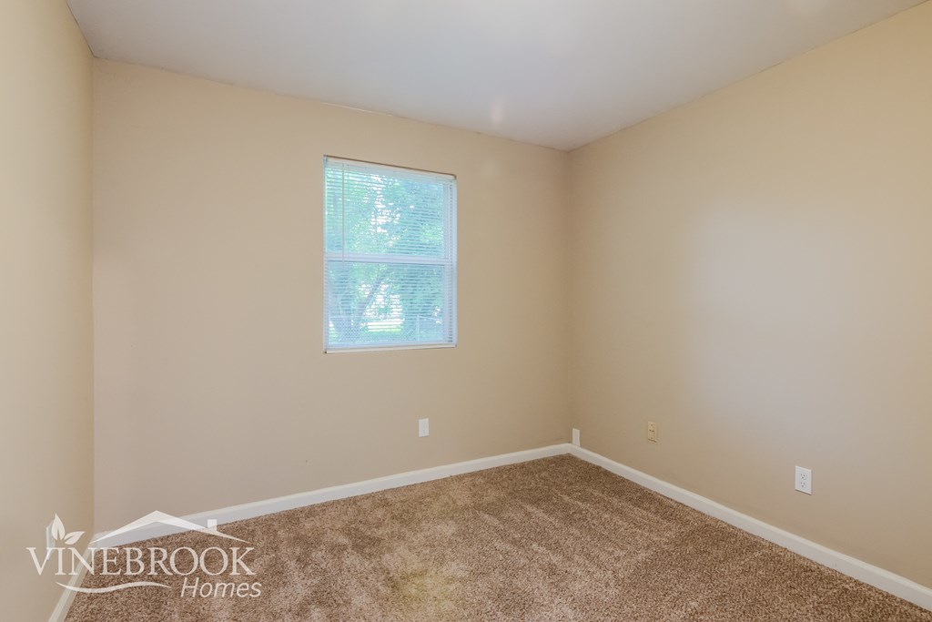 the upstairs bedroom has a carpeted floor and a window