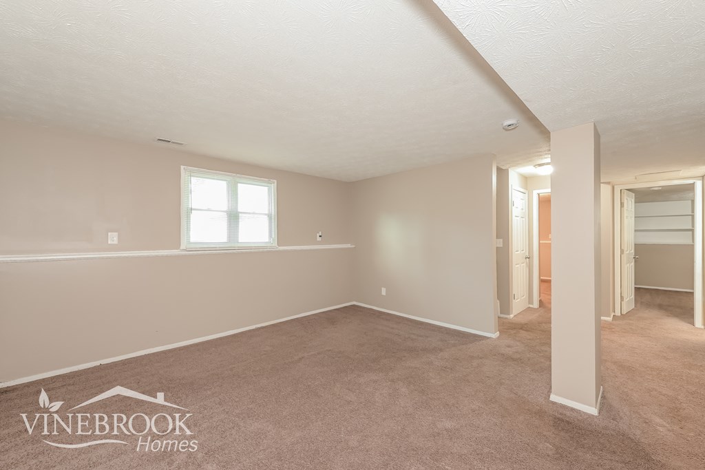 the living room and dining room of a home with carpeting and a window