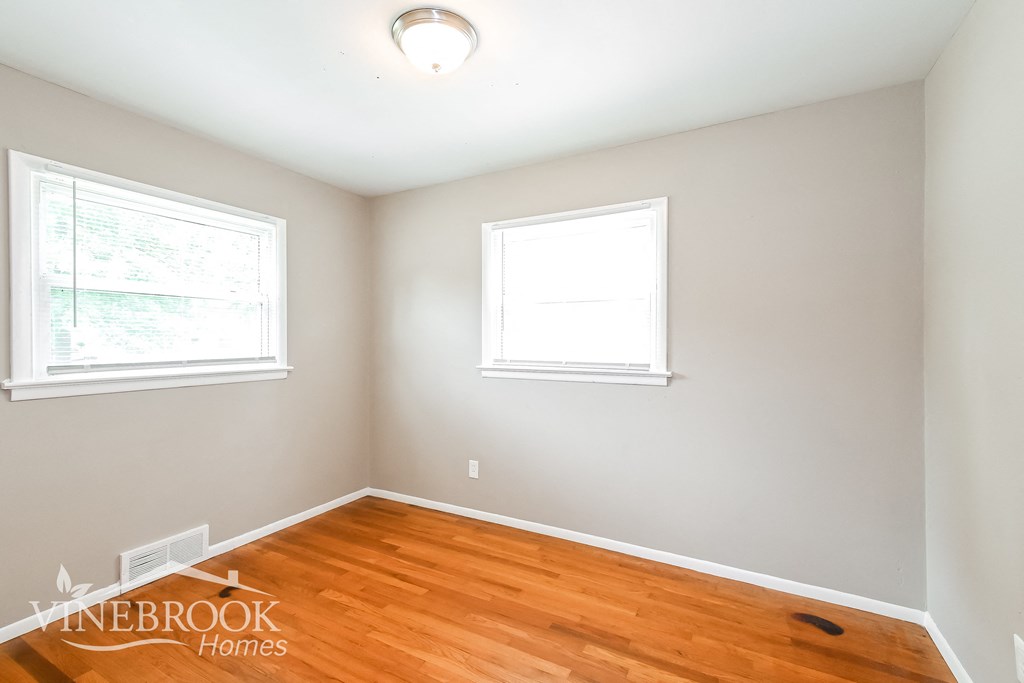 the second bedroom has a hardwood floor and two windows