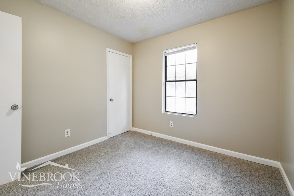 a bedroom with carpet and a door and a window