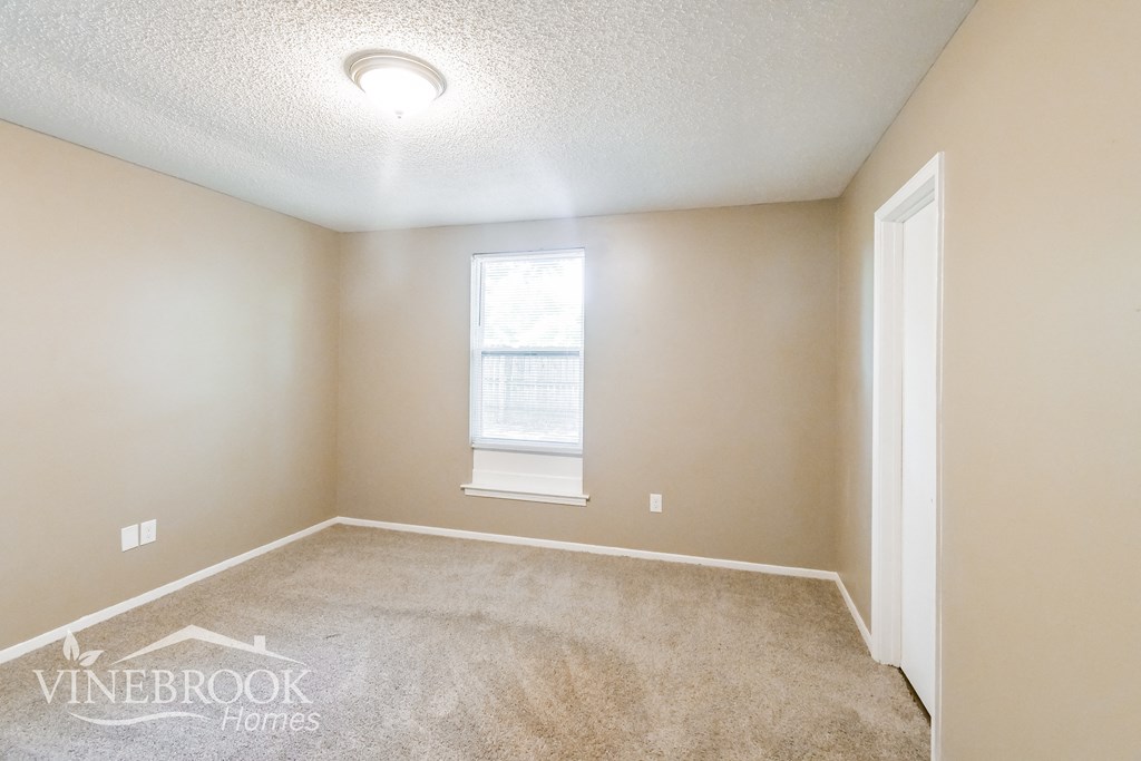 a bedroom with a carpeted floor and a window