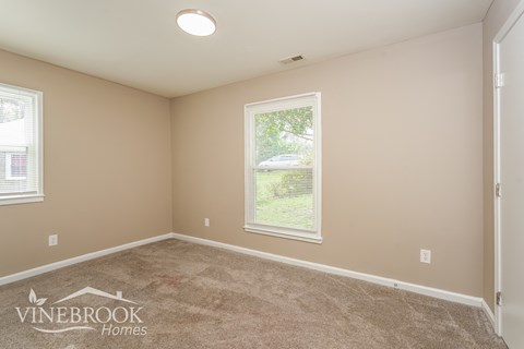 the living room of a new home with carpet and a window